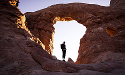 person standing in a natural stone archway
